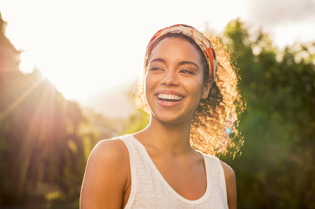 woman smiling and looking away at park during sunset.