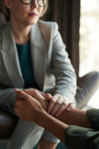 Close-up of a therapist keeping a hand on those of patient while comforting her during session