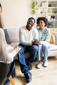 Young happy couple holding hands talking with therapist