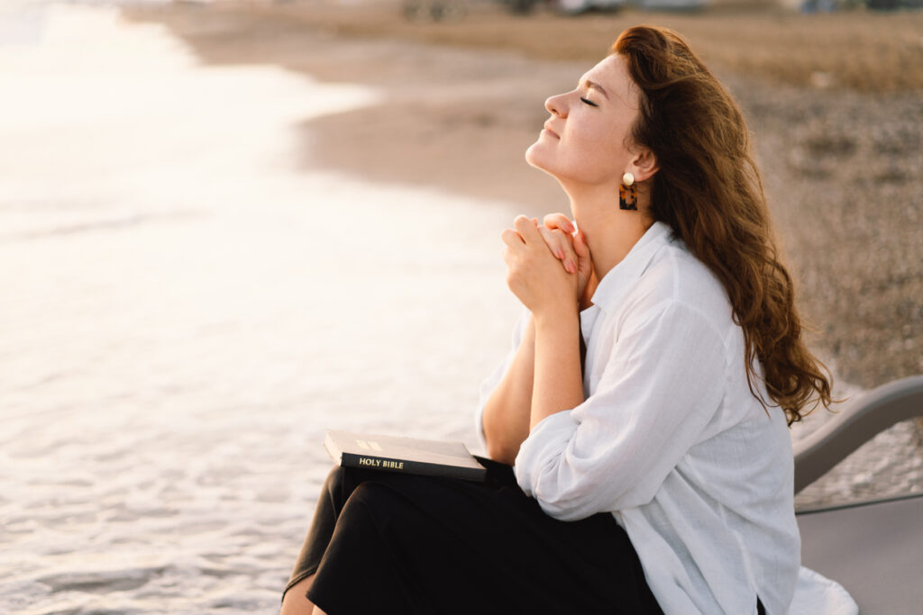 Woman closed her eyes, praying during beautiful sunset.
