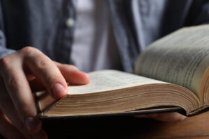 Man reading holy Bible at wooden table